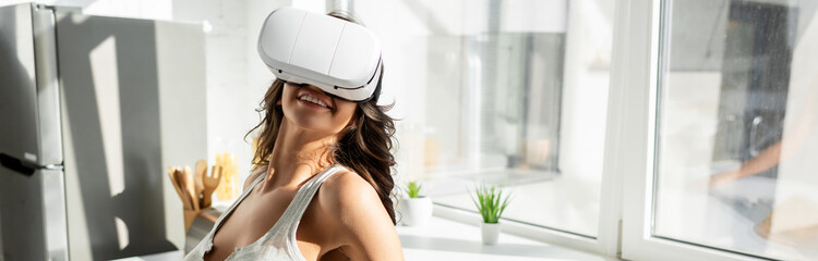 Positive girl using vr headset in kitchen, panoramic shot