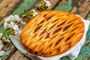 freshly homemade cherry pie and branch with flower on old wooden table