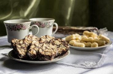 two plates with sweets (chocolate and cookies) on the background of which are two cups