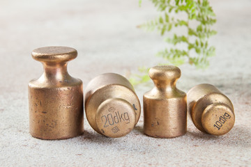 Four antique bronze weights for scales on concrete background.