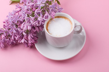 Morning Cup of coffee with a lilac flower. On a pink background.