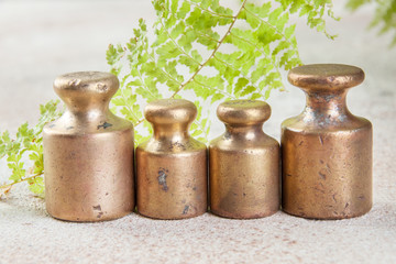 Four antique bronze weights for scales on concrete background.