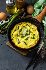 Healthy Asparagus Omelet. Egg omelet with asparagus and onions in a cast iron skillet on a stone countertop. Copy space.