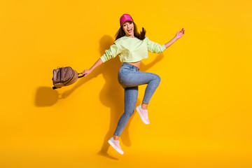 Fototapeta na wymiar Full size photo of energetic cheerful girl jump enjoy summer weekend journey hold backpack wear green stylish trendy clothes sneakers isolated over bright shine color background