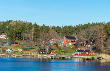 Fototapeta na wymiar Picturesque summer houses painted in traditional falun red on dwellings island of the Stockholm archipelago in the Baltic Sea in the early morning.