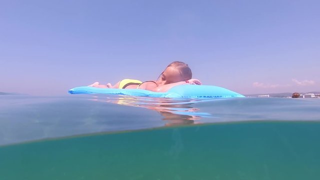 Cute child girl on air mattress in sea. Family vacation concept.