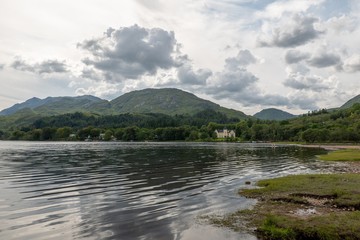 Shore of the Loch Shiel lake in Glenfinnan, Scotland with a house in the background