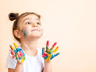 joyful little girl with painted hands. the child joyfully shows his palms painted with paints. painted children's palms