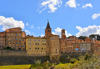 Fototapeta premium landscape with Anghiari italian medieval village city walls on green hill and blue sky in background. Arezzo, Tuscany Italy Europe.