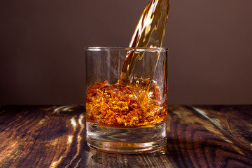 Whiskey is poured into a glass. Fiery alcoholic drink. Expensive alcohol.