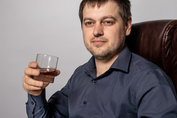 A 30-year-old man holds whiskey in a glass in his hand. Expensive alcoholic drink.