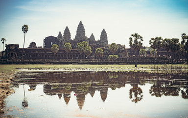 Obraz premium Cambodian temple monk and trees growing from the walls reflections in the water