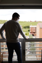 Isolated sad man using a mask in the window