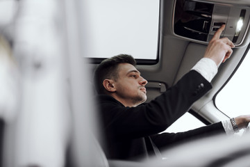 Young confident businessman is sitting in car