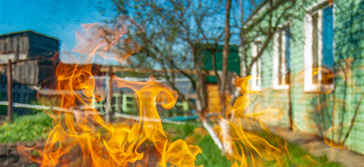 Bright flames on the background of houses and buildings. Danger from fire.