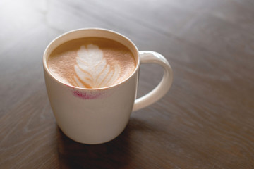 Lipstick mark on the top of coffee latte cup on wooden table