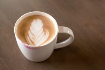 Lipstick mark on the top of coffee latte cup on wooden table