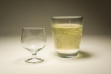An empty glass and a glass with sparkling water