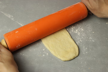 The dough is rolled out with a rolling pin on the table