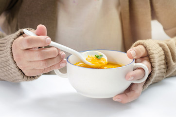 Woman holding a cup of butternut squash soup