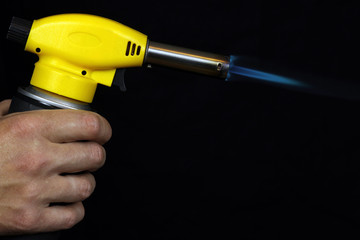 manual gas burner with blue flame on a black background