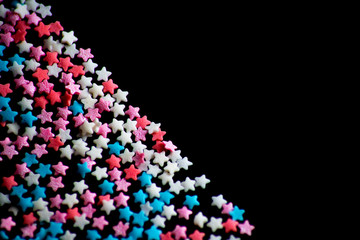 multicolored confectionery sprinkle in the form of stars on a black background