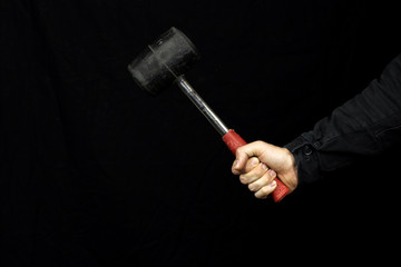 Rubber mallet in the hands of a worker on a black background. Copy space
