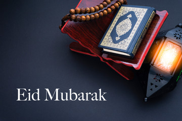 EID MUBARAK text with Holy Al Quran with written arabic calligraphy meaning of Al Quran, lantern...