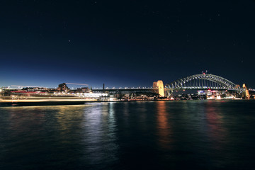 Long exposure of a ship crossing harbour bridge in Sydney night time with stars