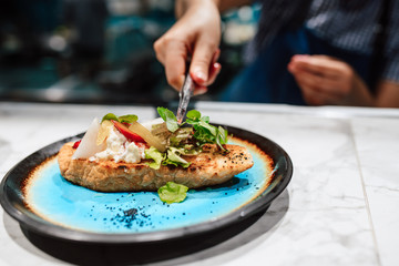 The chef cooks decorates the dish with greenery with tweezers. Italian bruschetta