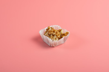 portion of walnuts in a paper muffin cup on a pink background