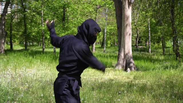 Japanese ninja in a black robe is training in the forest Portrait of a ninja in a mask