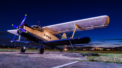 Old vintage classic airplane on small airfield in night time with clear sky. Abandoned biplane in...