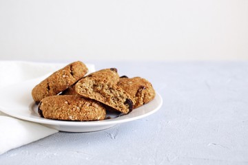 Oat cookies with raisin on white plate and light background.