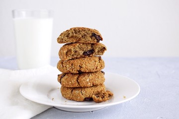 Oat cookies with raisin and glass of milk on light background.