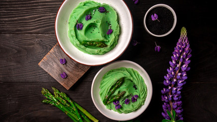 Creamy asparagus, spirulina and potatoes puree on a wooden table. Healthy food, ketogenic diet, diet lunch concept. Top view, overhead, banner