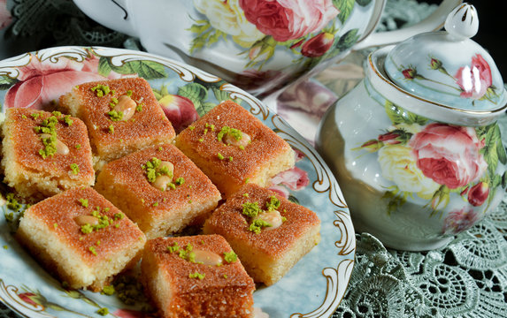 A slice piece of kunafa with tea port ramadan and Eid Arabic sweet pastries & dessert with creamy,cheese,pistachios in the dish. kunafa is a popular Arabian dessert that is often eaten during Ramadan