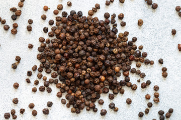 Organic dried Black Peppercorns on light concrete or stone background close-up. Pepper. Spices and seasonings. Selective focus, top view