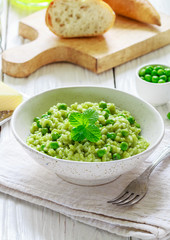 Rice with spinach, peas, Parmesan cheese and mint. Green risotto. A traditional dish of Mediterranean (Italian) cuisine. Delicious healthy lunch or dinner for gourmets. Selective focus