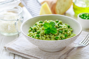 Rice with spinach, peas, Parmesan cheese and mint. Green risotto. A traditional dish of Mediterranean (Italian) cuisine. Delicious healthy lunch or dinner for gourmets. Selective focus