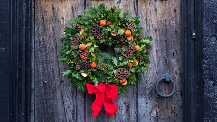 Christmas door wreath, a natural arrangement of flowers, berries, fruits and leaves fasten on a ring and set on a house entrance door as decoration, a winter holidays symbol of unending circle of life