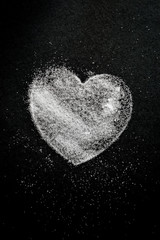 Heart shape silhouette made with sugar with copy space on a black background