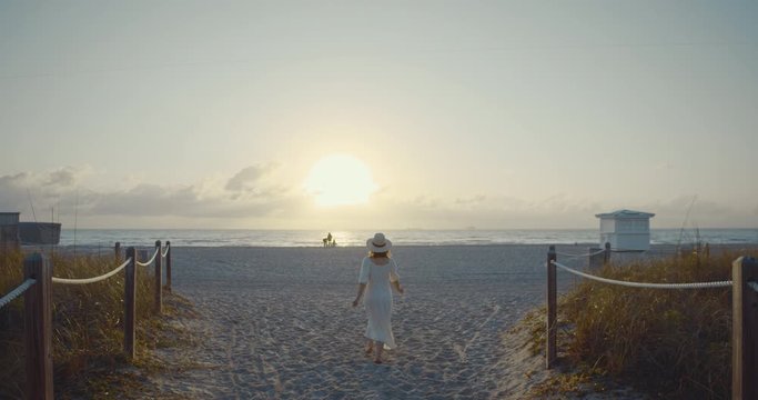 Young woman in a white dress running to the beach. Shot on Black Magic Cinema Camera