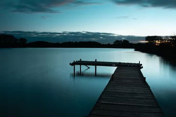 Fototapeten Pier Wooden jetty on a calm blue lake, sky after sunset  © darekb22
