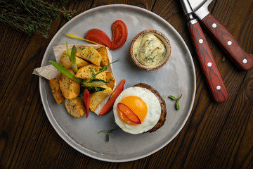 Beef medallions with egg, potatoes and peppers on a wooden background