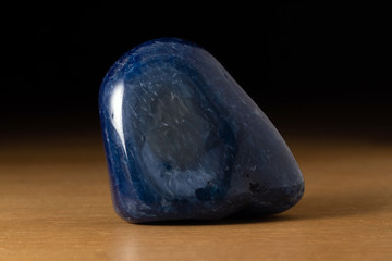 Polished blue agate gemstone from Brazil over a wooden table