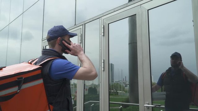 Courier delivers pizza in cardboard boxes to the office, the process of food delivery, food delivery man at work, man confirms the order by smartphone.