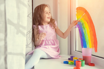 child at home draws a rainbow on the window. Flash mob society community on self-isolation quarantine pandemic coronavirus. Children create artist paints creativity vacation
