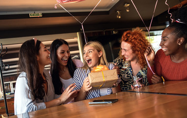Group of girls surprise their girlfriend with a birthday party at restaurant.