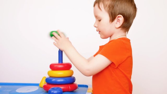 A cute little boy takes apart and collects color pyramid